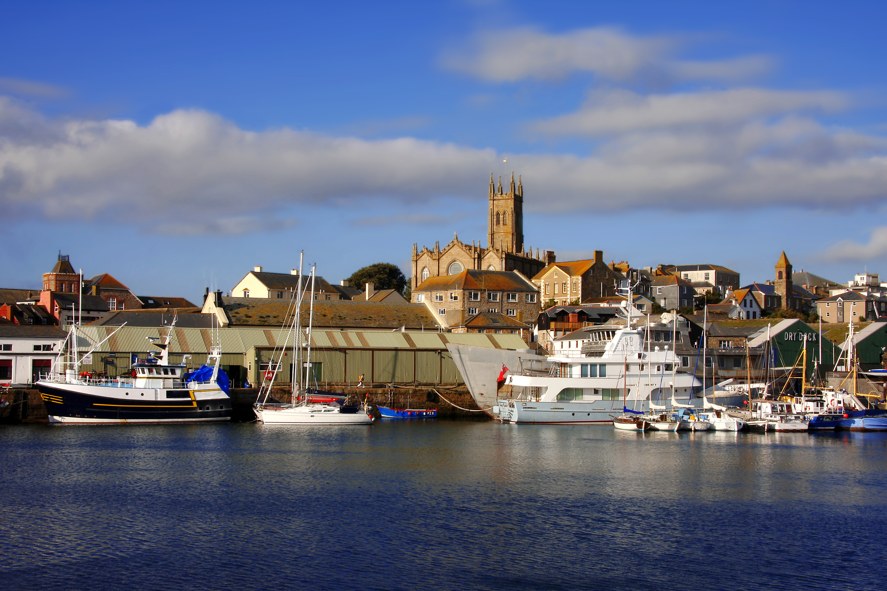 Idyllisk solnedgang over marinaen i Penzance med både og fyrtårn langs Cornwalls kystlinje i England