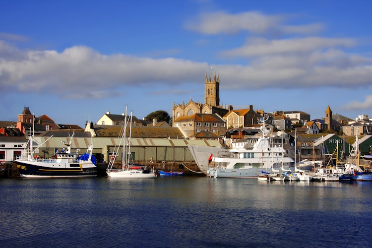 Idyllisk solnedgang over marinaen i Penzance med både og fyrtårn langs Cornwalls kystlinje i England