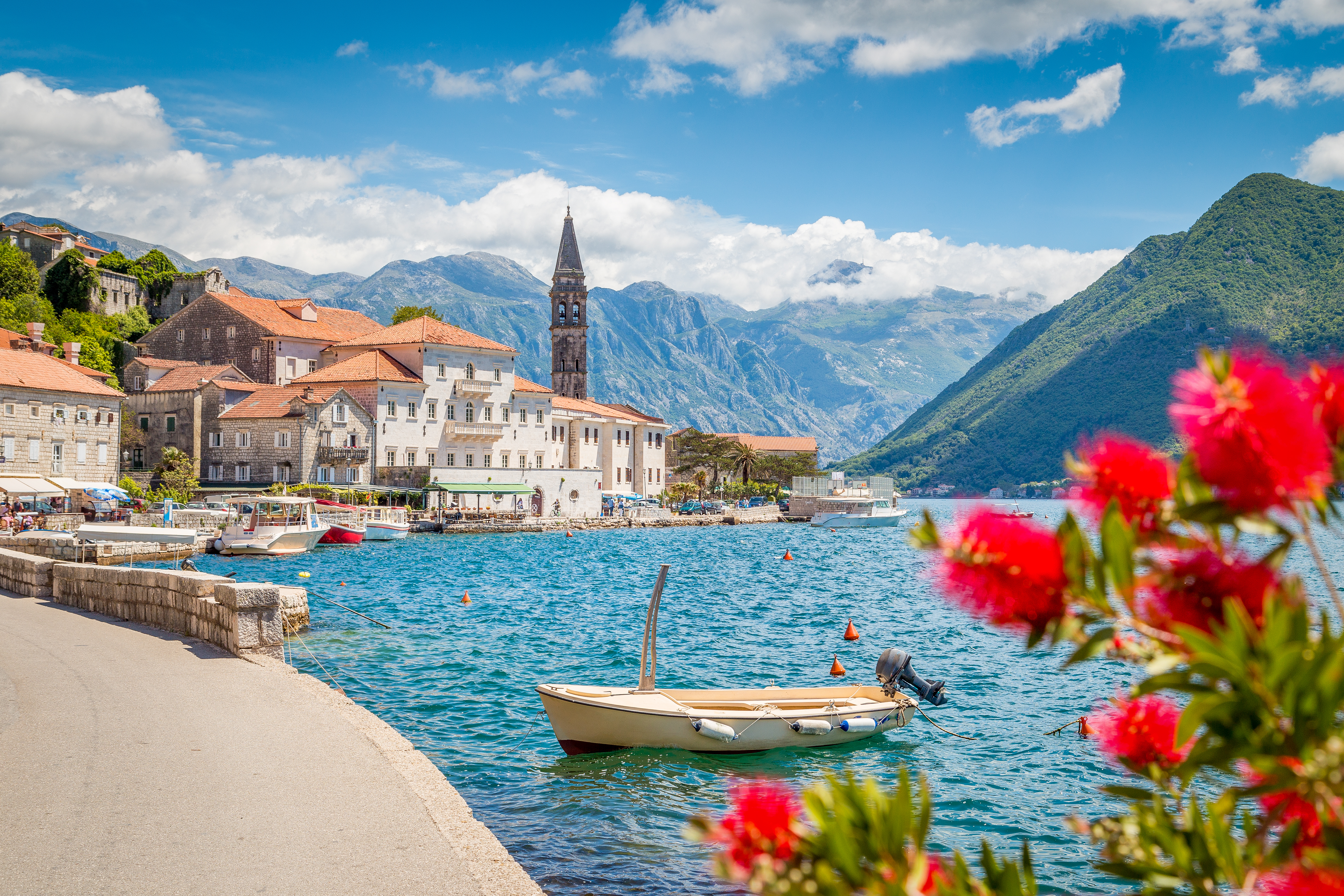 Idyllisk panoramaudsigt over den historiske by Perast ved Kotor-bugten med blomstrende blomster på en solrig sommerdag i Montenegro