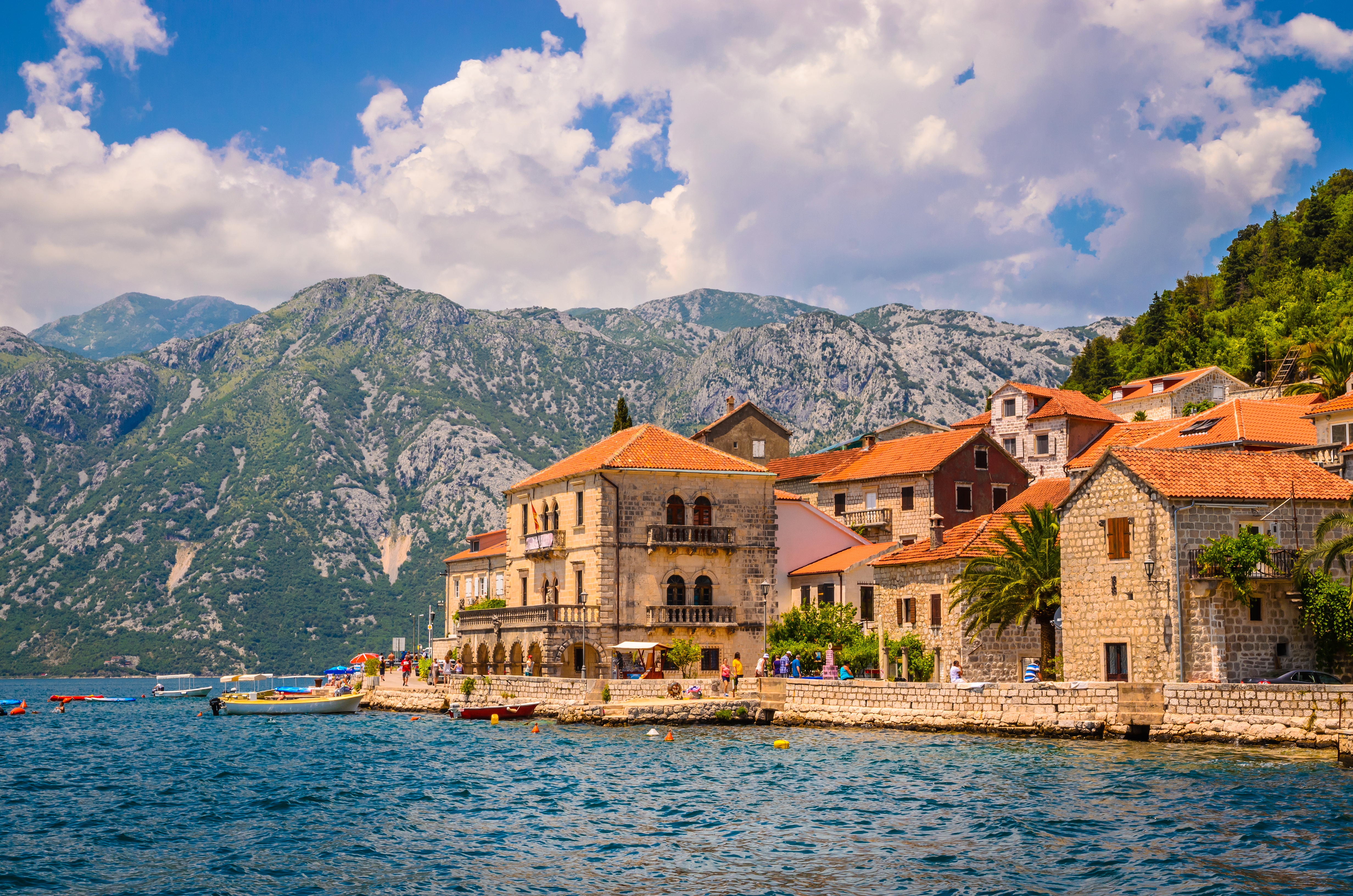 Historiske stenbyggelser langs Kotor Bugt i Montenegro med dramatiske bjerge i baggrunden