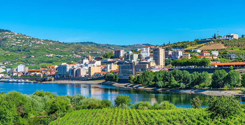 Udsigt over Peso da Régua ved Douro-floden omgivet af terrasse-vingårde og grønne bakker i Portugals Douro-dal