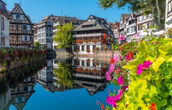 Farverige bindingsværkshuse med blomster langs kanalen i Petite France-kvarteret i Strasbourg, Frankrig