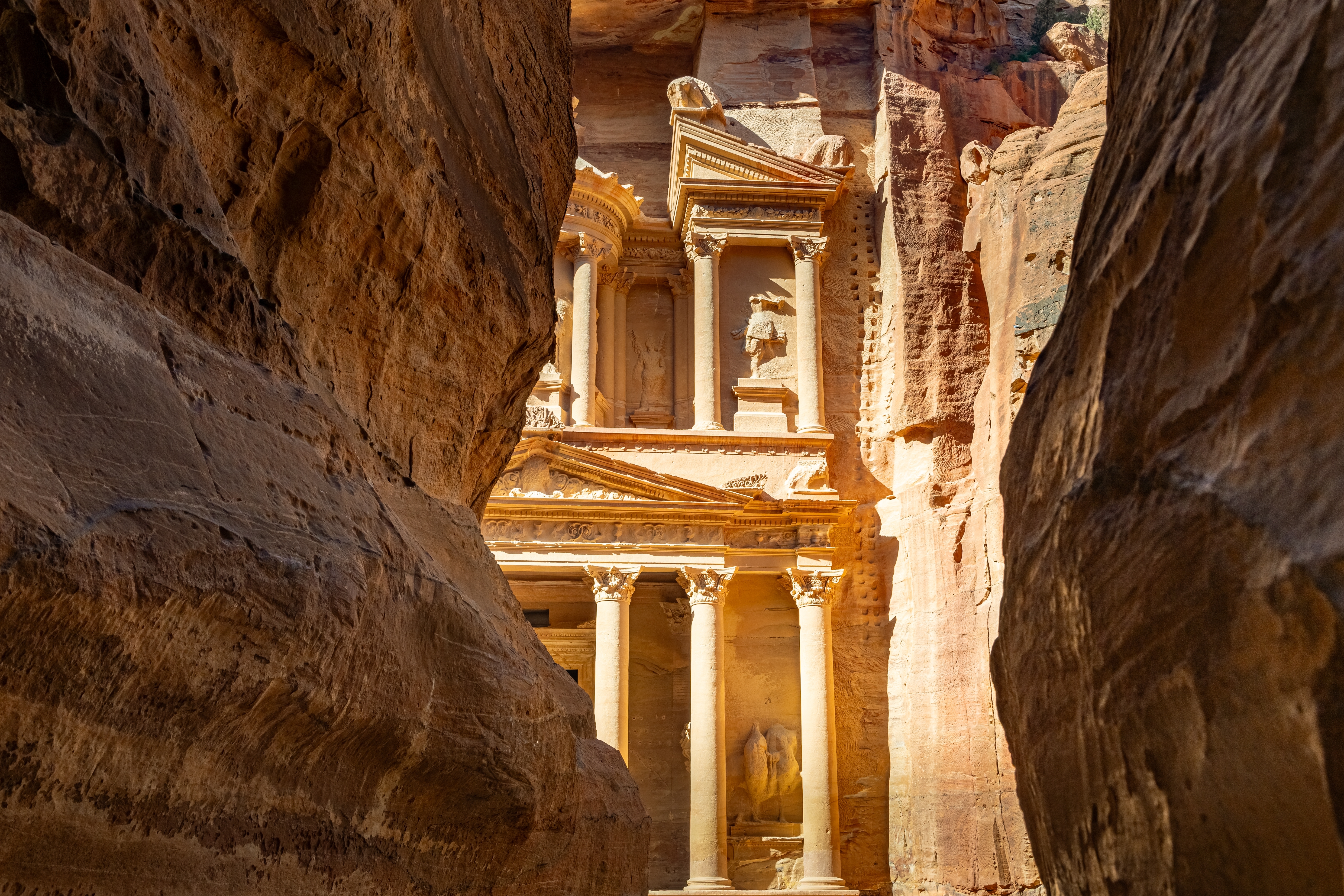Skatkammeret i Petra set gennem den smalle Siq-kløft med gyldne sandstensklipper, der indrammer det antikke nabatæiske monument i Jordan