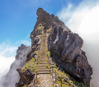 Spektakulær bjergsti mellem Pico Arieiro og Pico Ruivo med stentrapper langs de dramatiske klippeformationer omgivet af skyer på Madeira