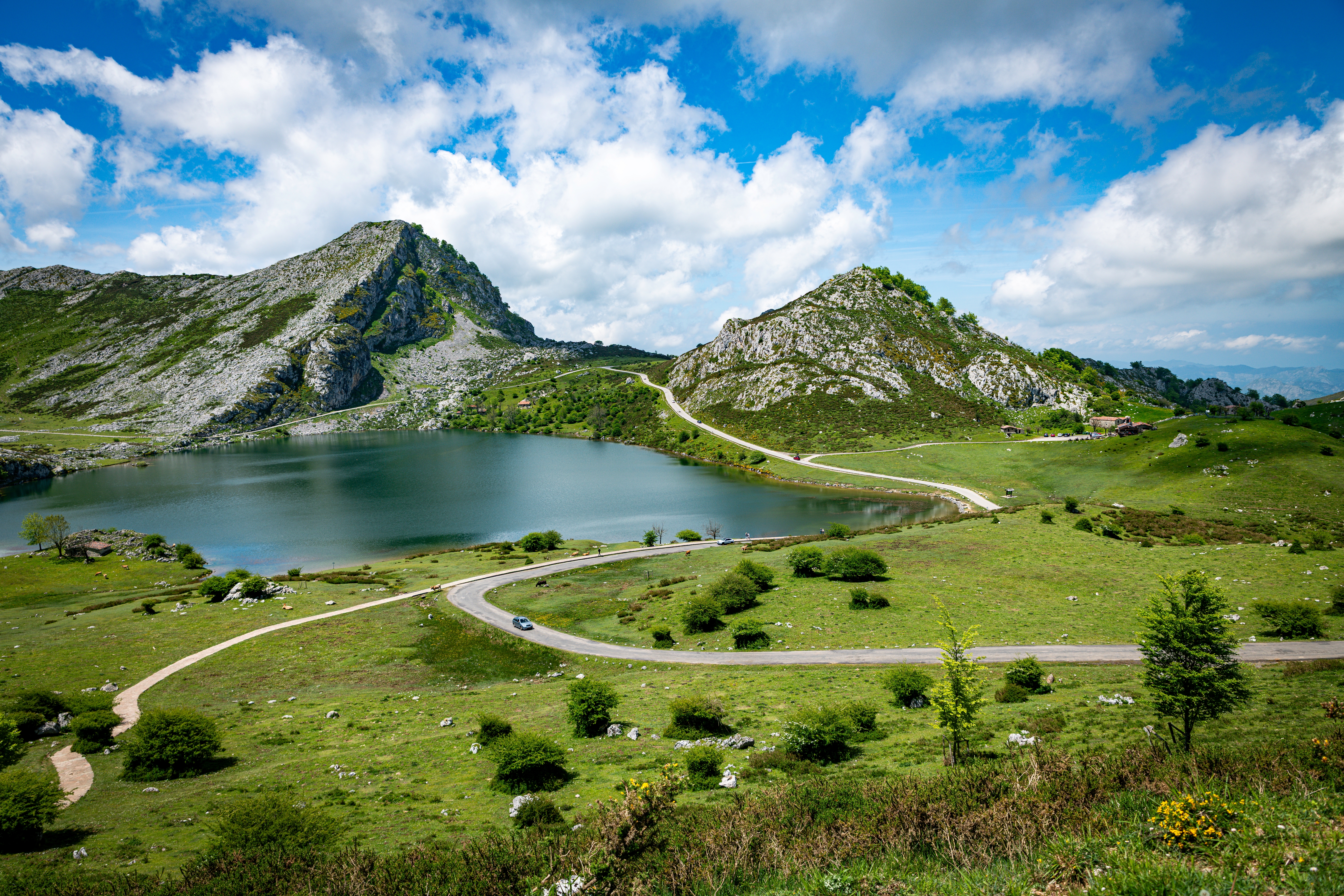 Snoende bjergvej gennem Picos de Europa med sø og grønne marker i Asturias, Spanien