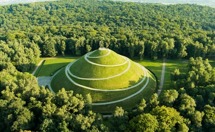 Luftfoto af Pilsudskis Høj i Krakow med karakteristiske spiralformede stier på en grøn bakke omgivet af skov, også kendt som Uafhængighedshøjen
