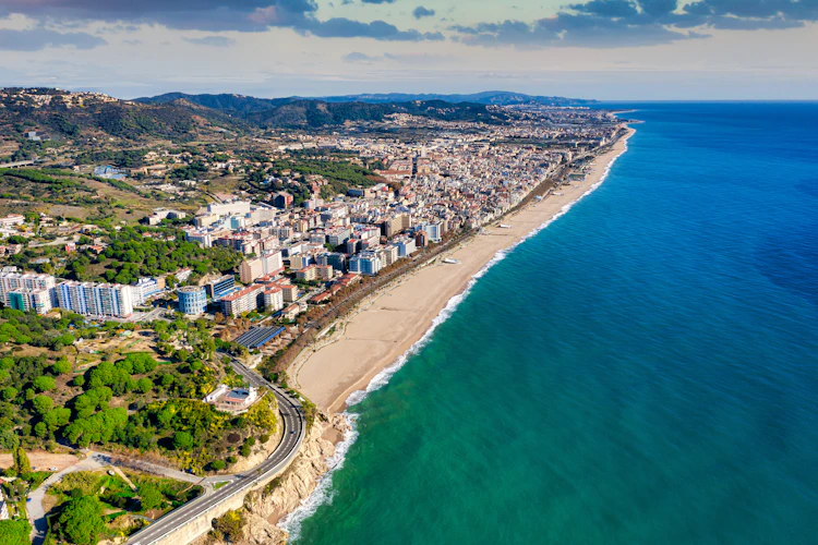 Luftfoto af Pineda de Mar med turkisblåt Middelhav, lang sandstrand og ferieresort i Catalonien, Spanien
