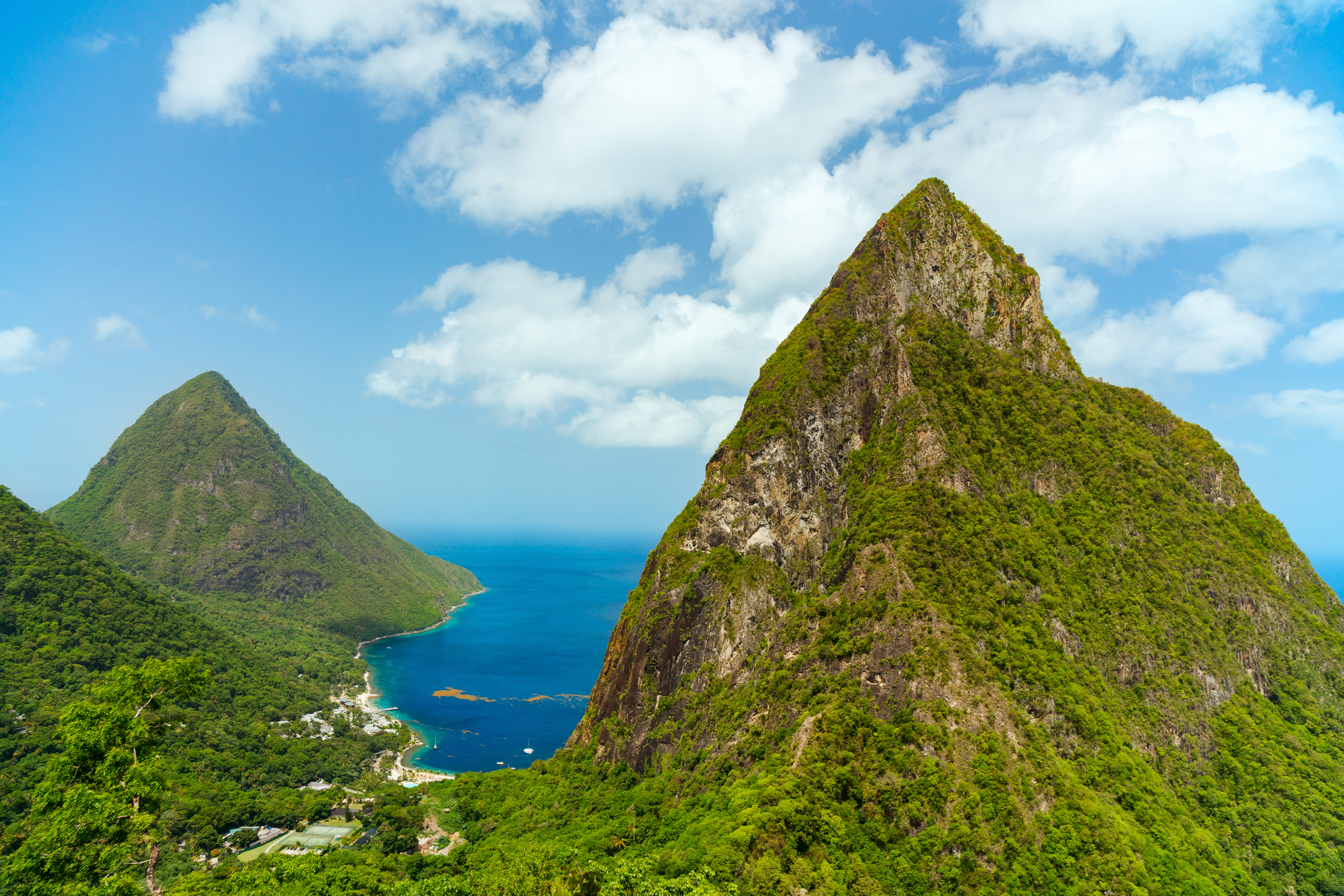 Betagende udsigt over de ikoniske Piton-bjerge der rejser sig fra det turkisblå hav på Saint Lucia i Caribien, et tropisk paradis for naturelskere