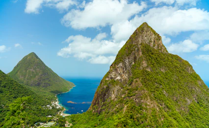 Betagende udsigt over de ikoniske Piton-bjerge der rejser sig fra det turkisblå hav på Saint Lucia i Caribien, et tropisk paradis for naturelskere