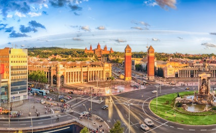 Panoramaudsigt over Plaça d'Espanya i Barcelona med den ikoniske fontæne, venetianske tårne og Nationalpaladset ved Montjuïc-bjerget