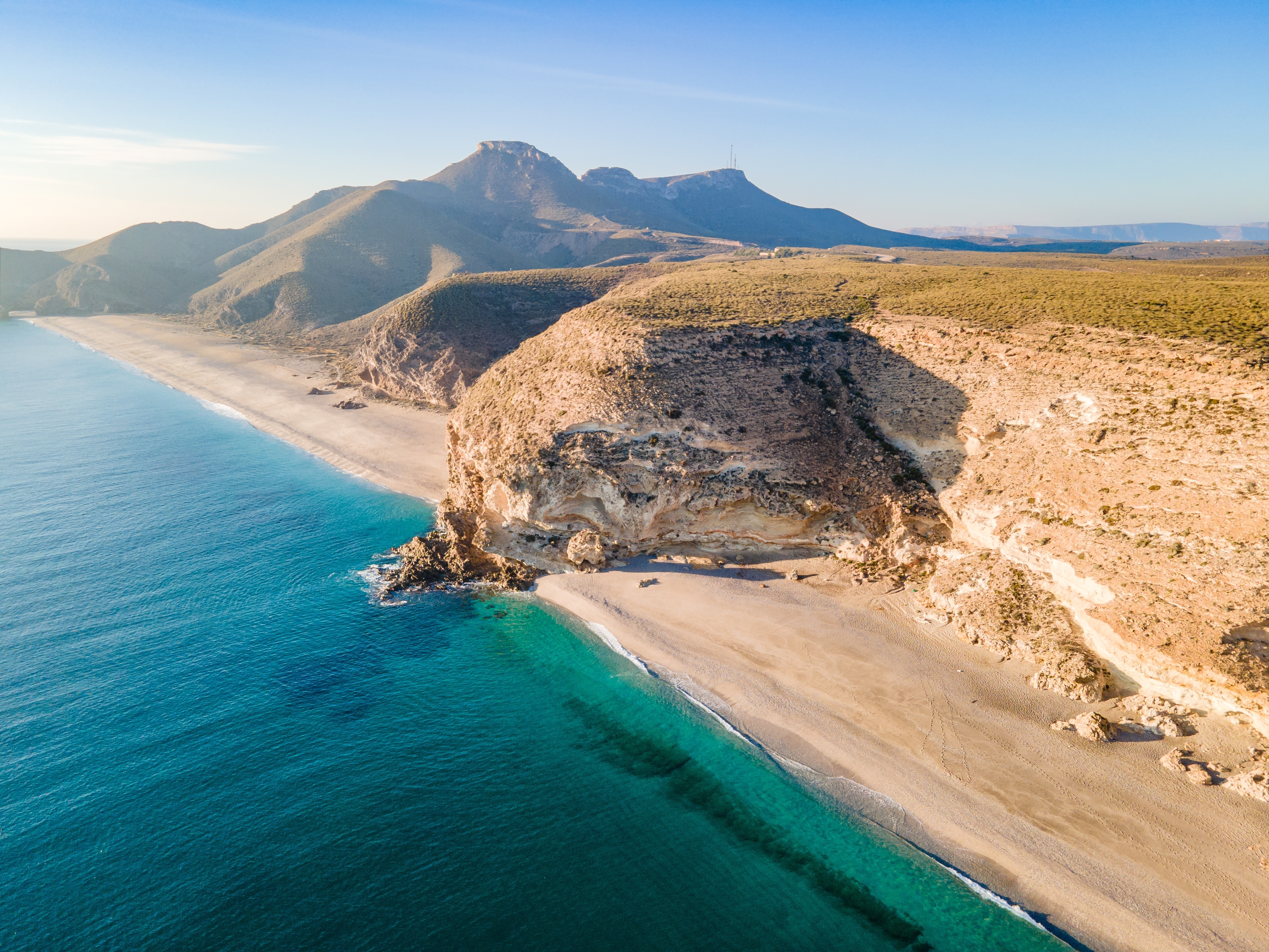 Betagende solopgang over Playa de los Muertos stranden med krystalklart turkisblåt vand og hvidt sand omgivet af klippeformationer i Cabo de Gata naturpark, Almeria, Spanien