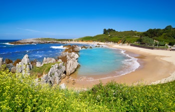 Idyllisk bugt ved Playa de Toro stranden i Llanes, Asturien med turkisblåt vand og gyldent sand omgivet af klipper