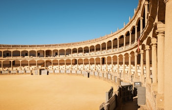 Den historiske tyrefægterarena Plaza de Toros i Ronda, Andalusien med karakteristisk neoklassisk arkitektur og dobbelte buerækker under blå himmel
