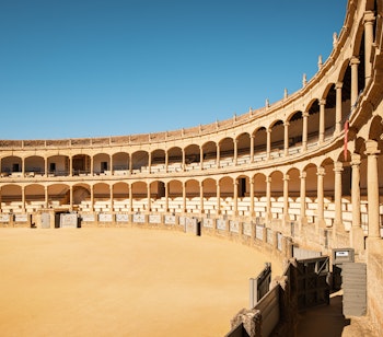 Den historiske tyrefægterarena Plaza de Toros i Ronda, Andalusien med karakteristisk neoklassisk arkitektur og dobbelte buerækker under blå himmel