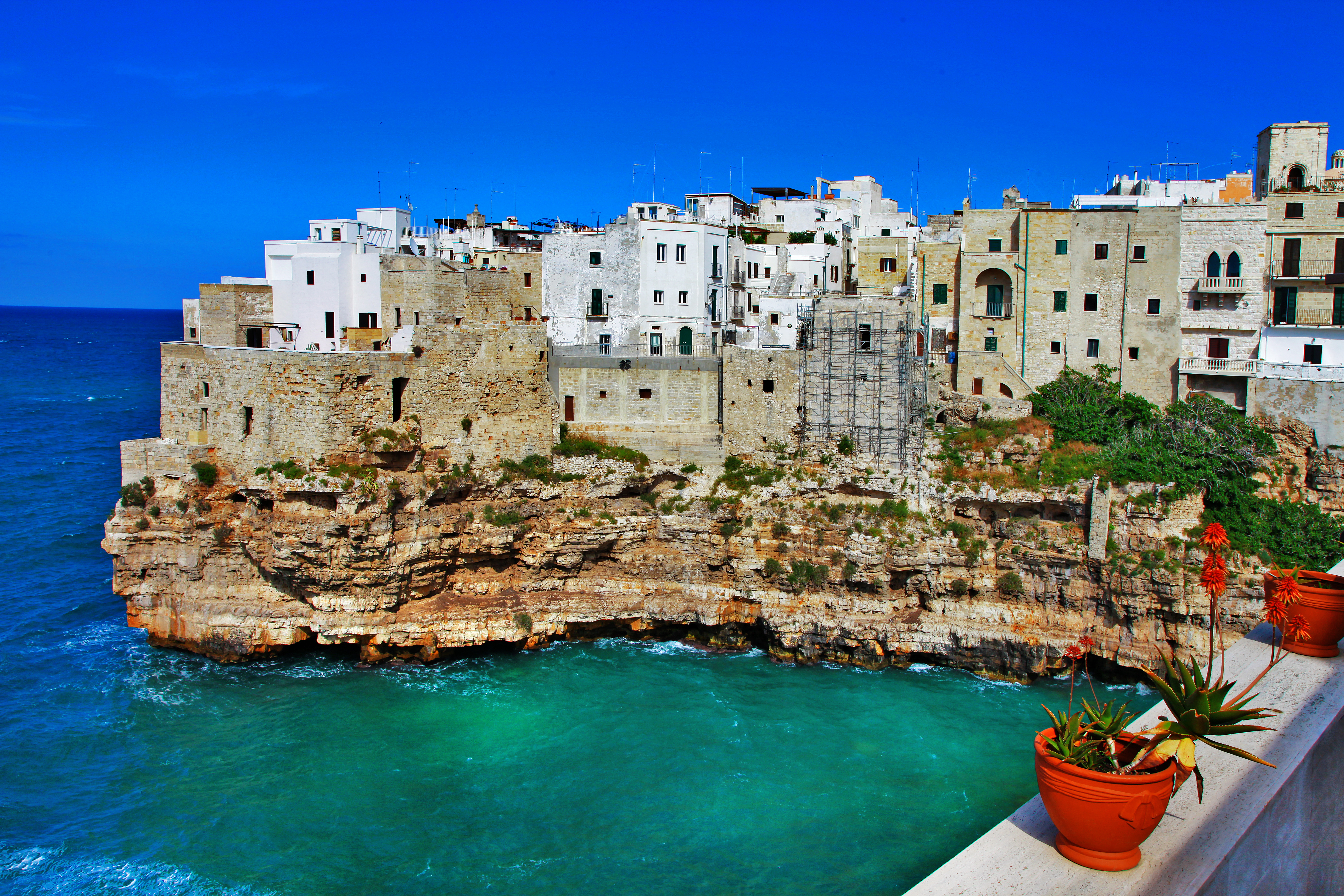 Smukke hvide huse på klipper i Polignano a Mare, Puglia, Italien med turkisblåt hav