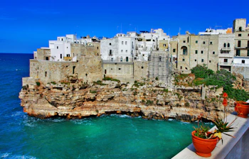 Smukke hvide huse på klipper i Polignano a Mare, Puglia, Italien med turkisblåt hav