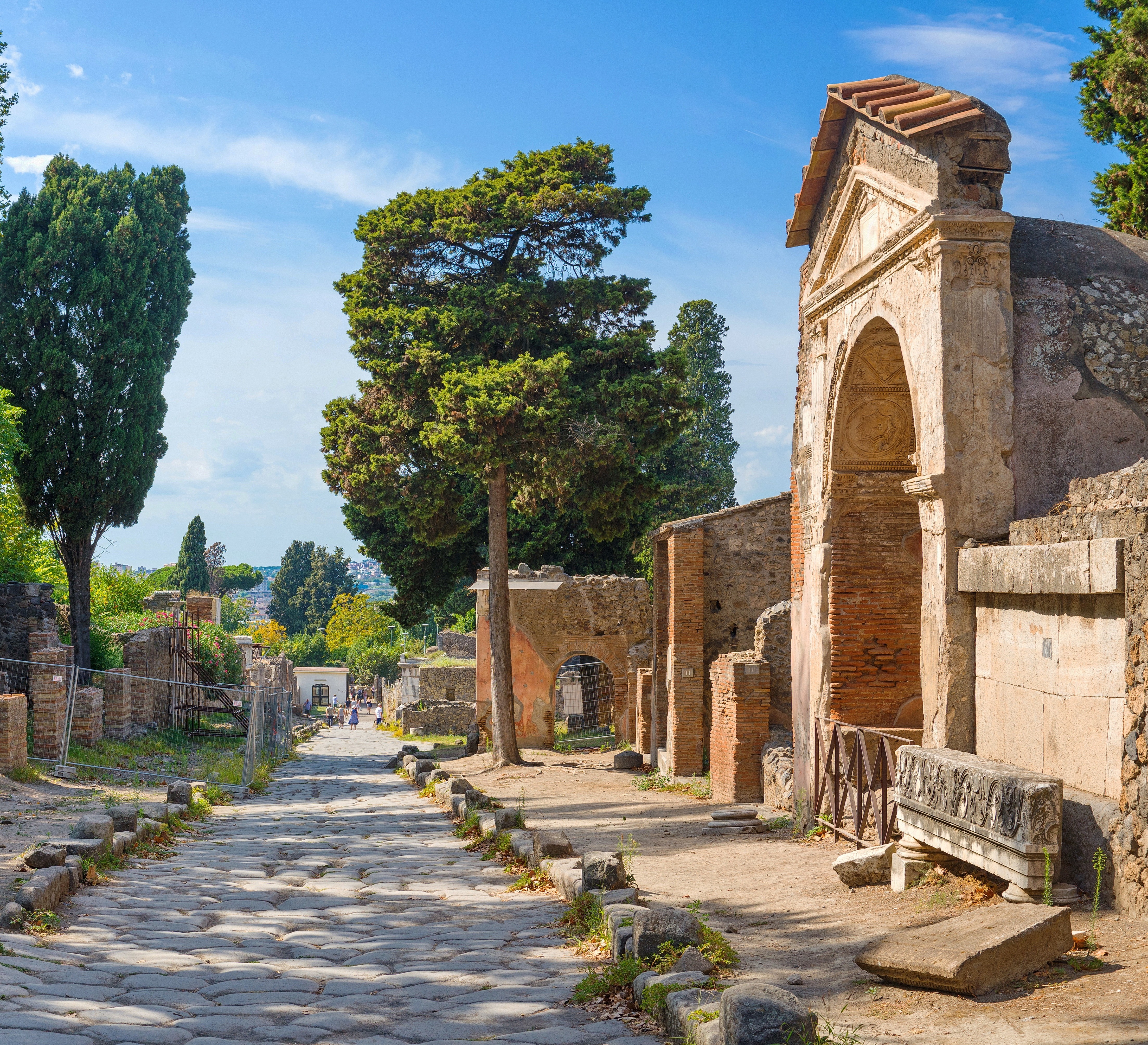 Antikke romerske ruiner i Pompeii med stenbro og søjler under blå himmel