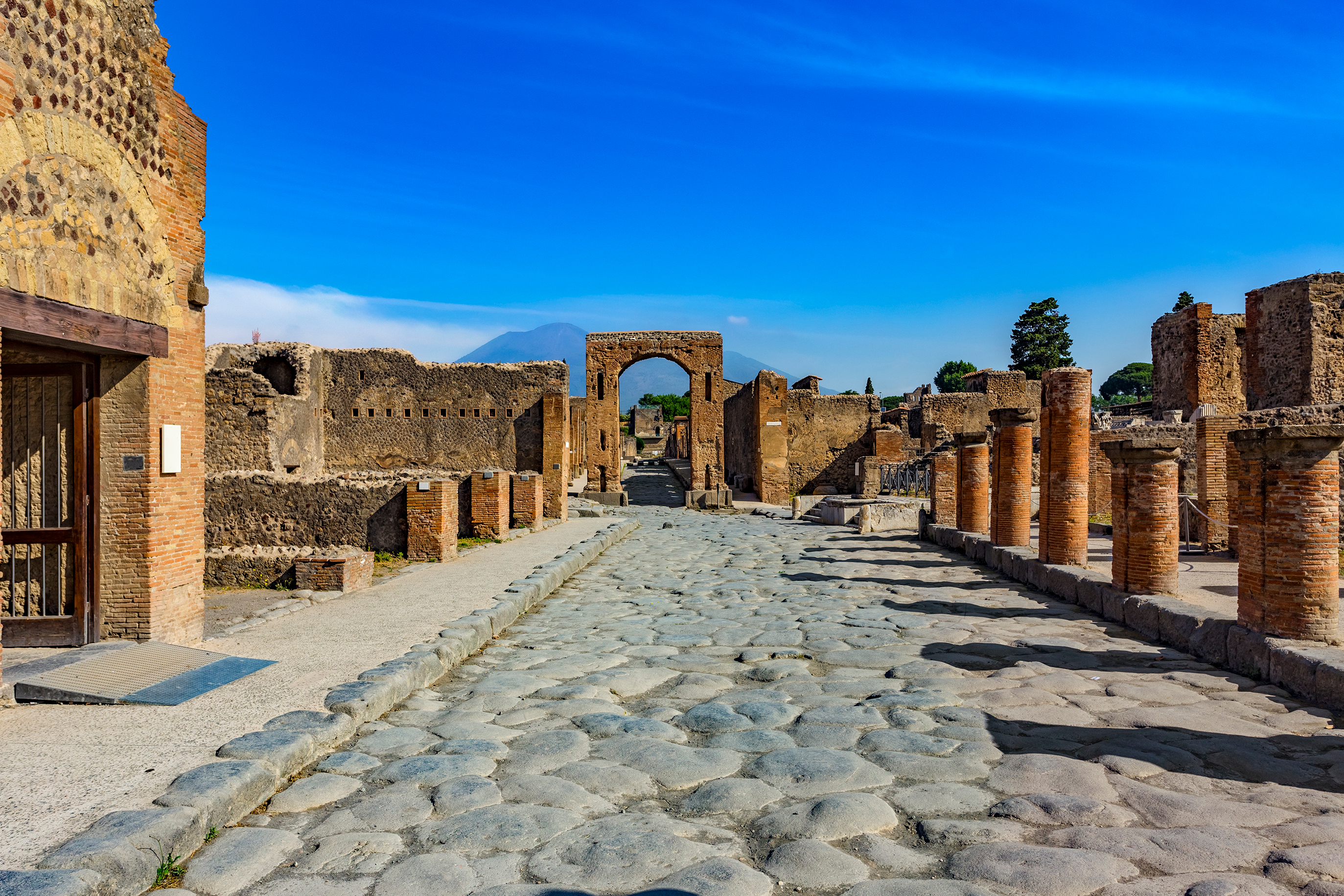 Den brolagte Via del Foro i antikke Pompeii med Caligulas triumfbue og Vesuv i baggrunden, UNESCO Verdensarv i Italien
