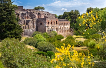 De historiske ruiner af Pompeji med antikke romerske bygninger, frodige grønne områder og klar himmel - en ikonisk UNESCO-verdensarvsdestination nær Napoli