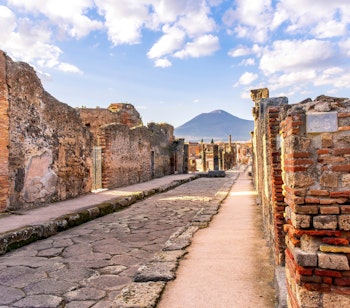 Historiske ruiner fra Pompeji med Vesuv-vulkanen og dramatisk skyet himmel i baggrunden, Napoli, Italien
