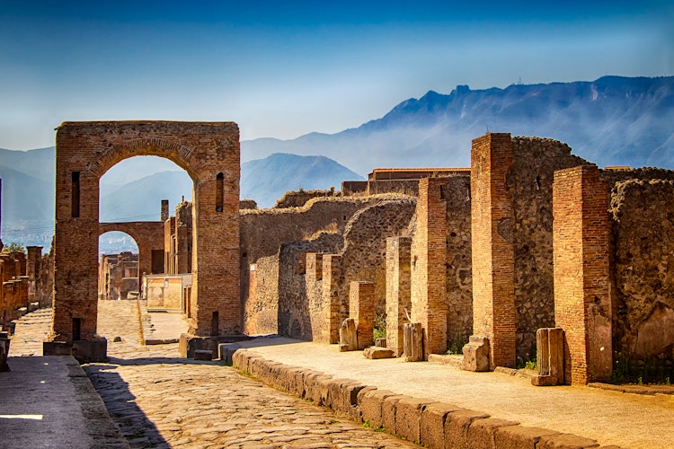 Antikke romerske ruiner i Pompeji med Vesuv i baggrunden, historisk arkæologisk seværdighed i Italien