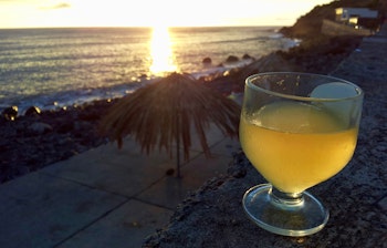 Traditionel Poncha-cocktail nydes ved solnedgang over havet i Paul do Mar på Madeira