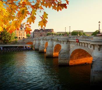 Den historiske Pont Neuf bro over Seinen i Paris med gyldne efterårsblade og klassisk fransk arkitektur
