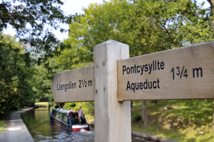 Smal flodbåd sejler forbi vejskilt til Pontcysyllte Akvadukt på Llangollen Kanalen i Wales