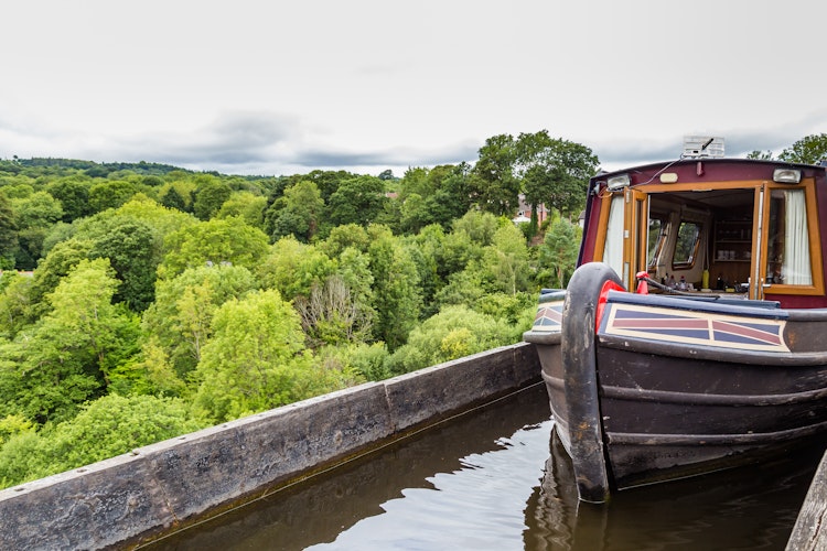 Historisk kanalbåd krydser Pontcysyllte Akvædukten i Wales - verdens højeste akvædukt designet af Thomas Telford med udsigt over den grønne Llangollen-dal