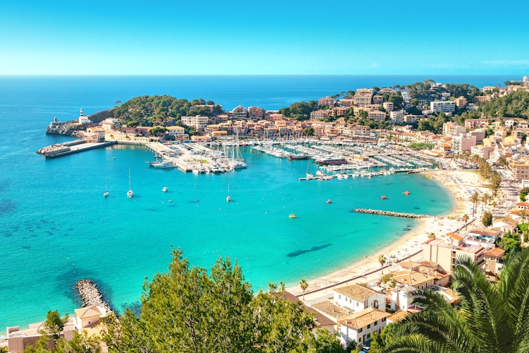 Idyllisk udsigt over havnen i Port de Soller på Mallorca med farverige både, azurblåt Middelhav og den charmerende kystby omgivet af bjerge