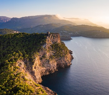 Luftfoto af det historiske Torre Picada vagttårn beliggende på de dramatiske klipper med udsigt over det dybe blå Middelhav langs Port de Sollers kystlinje på Mallorca