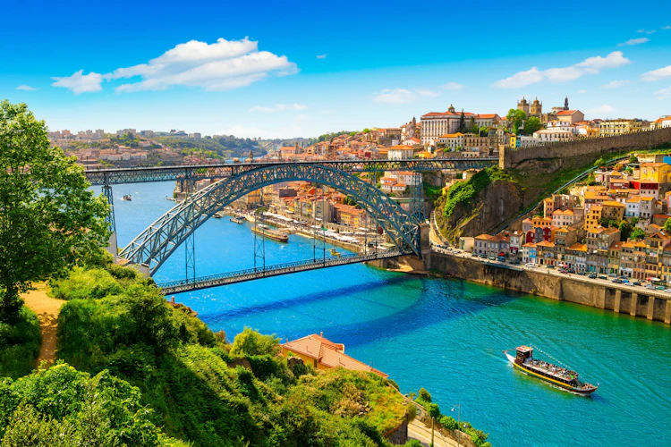 Dom Luis I broen over Douro-floden i Porto, Portugal med historiske bygninger og turistbåd