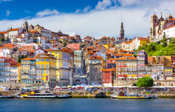 Farverige huse langs Douro-floden i Porto med traditionelle rabelo-både og historisk arkitektur