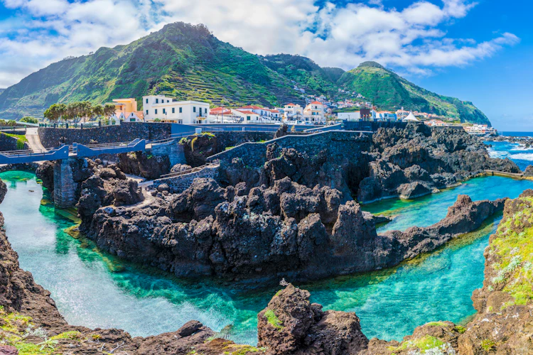 Porto Moniz naturlige vulkanske bassiner med turkisblåt vand og traditionel portugisisk landsby på Madeira