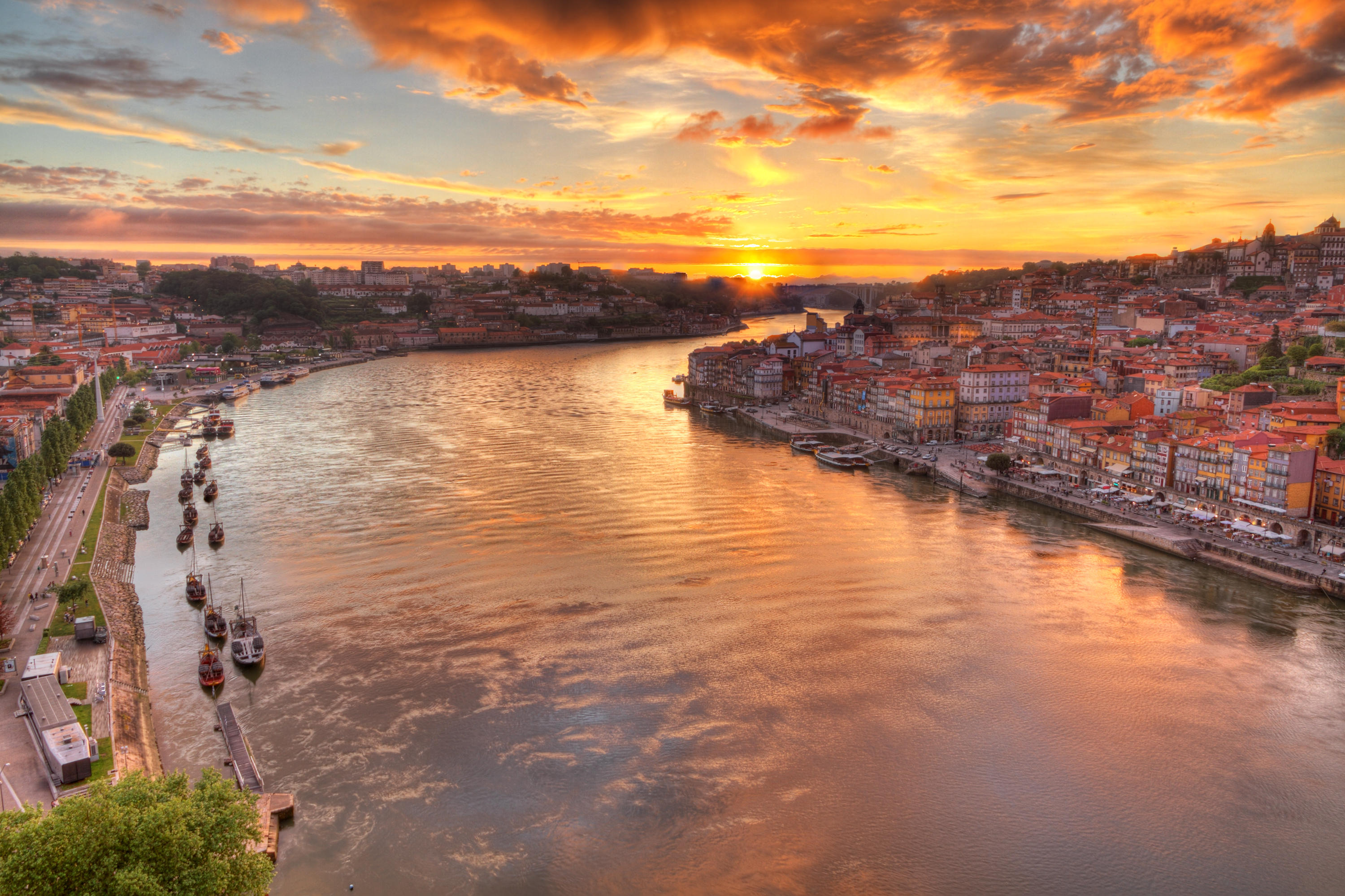 Panorama over den gamle bydel i Porto ved Douro-floden med traditionelle portvinsbåde i solnedgang, Portugal