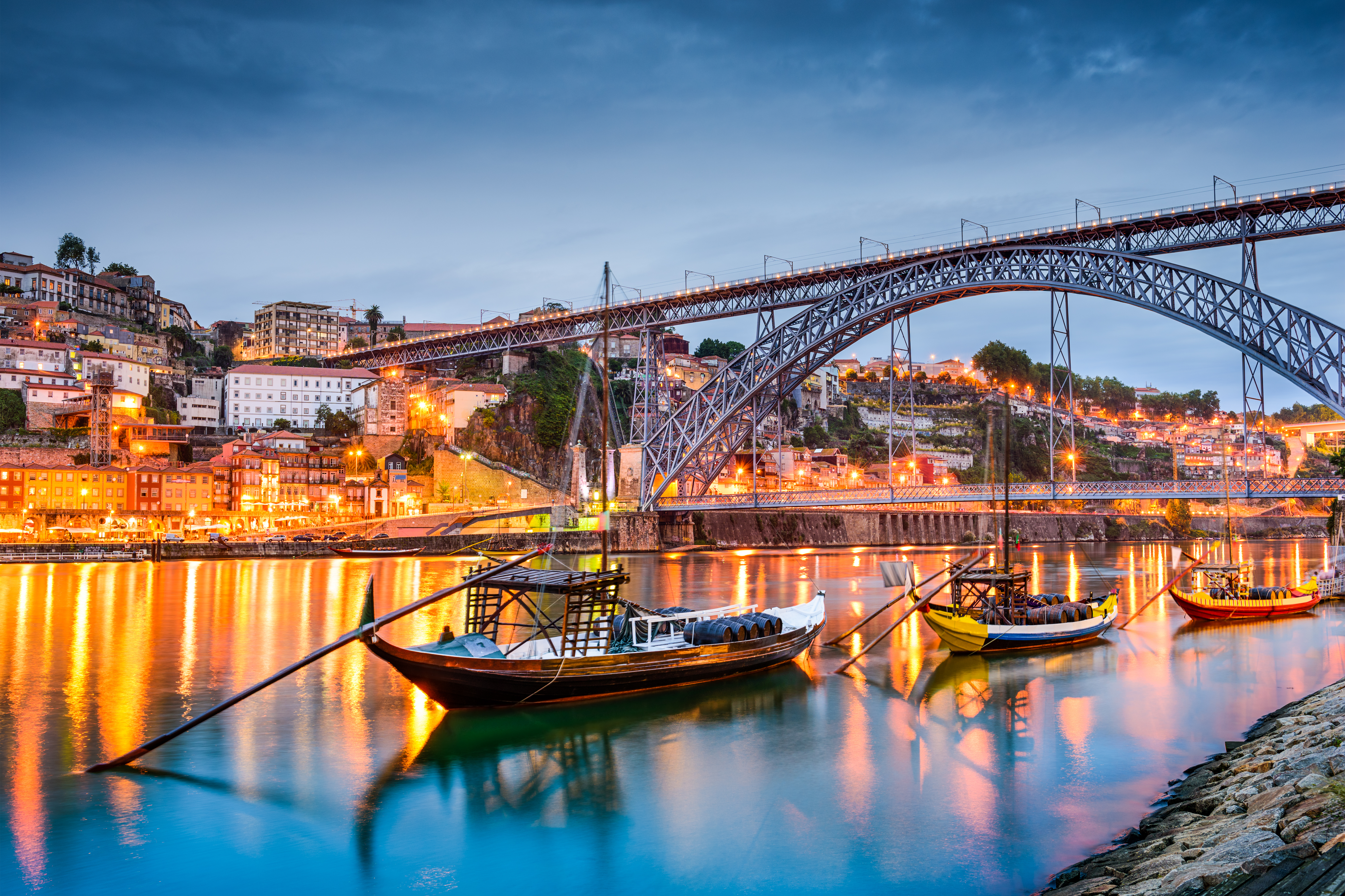 Porto byens smukke skyline ved aftentid med traditionelle Rabelo-både på Douro-floden, der historisk transporterede portvin
