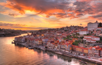 Betagende panoramaudsigt over Portos gamle bydel ved Douro-floden med traditionelle portvinsbåde i solnedgangen, Portugal