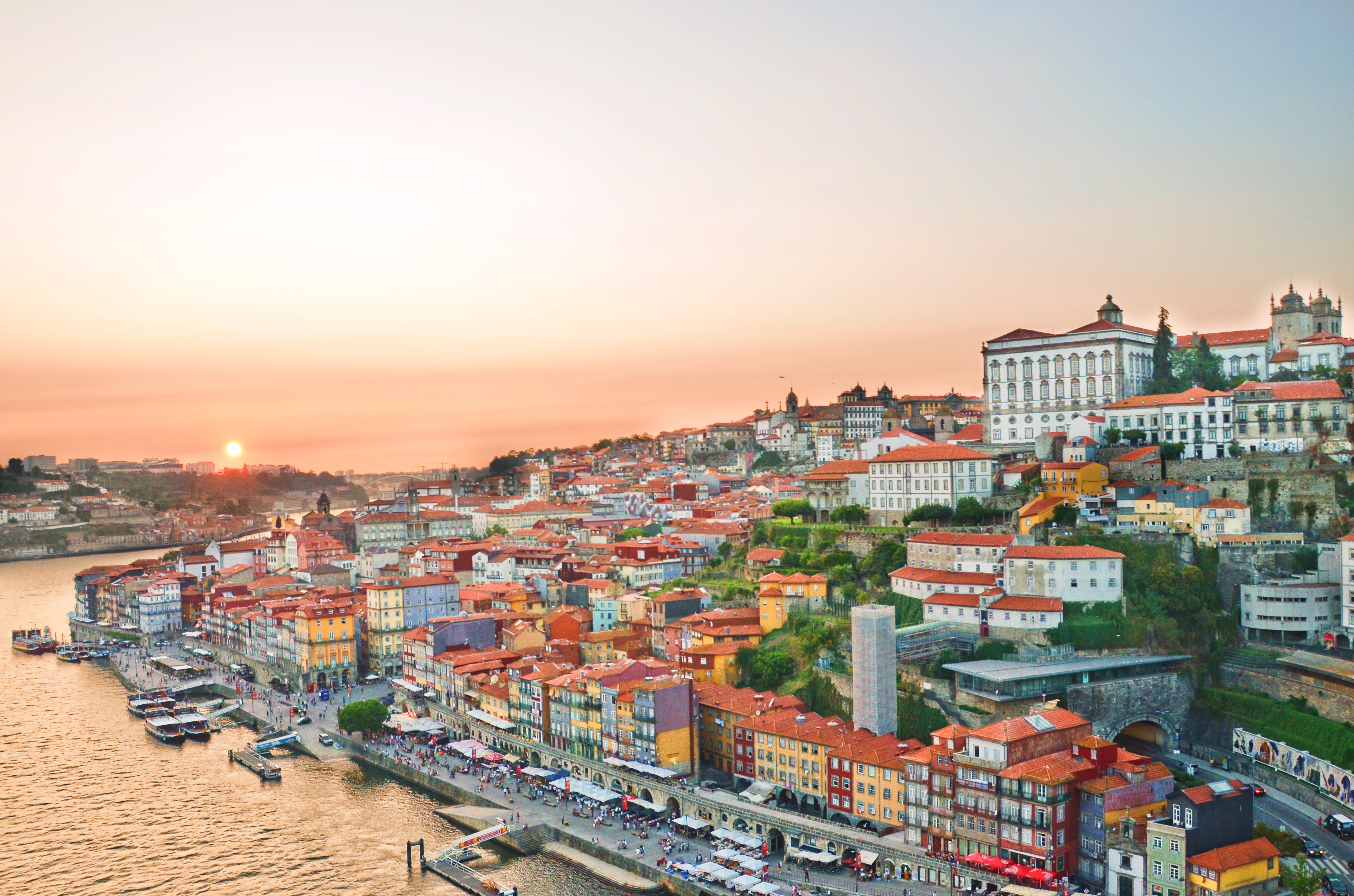 Betagende udsigt over Portos historiske centrum ved solnedgang med farverige bygninger langs Douro-floden og Porto Katedralen på bakketoppen