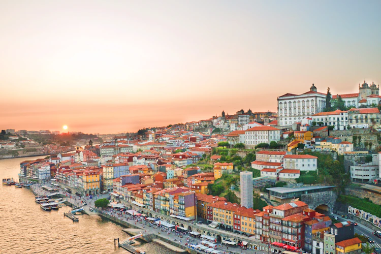 Betagende udsigt over Portos historiske centrum ved solnedgang med farverige bygninger langs Douro-floden og Porto Katedralen på bakketoppen