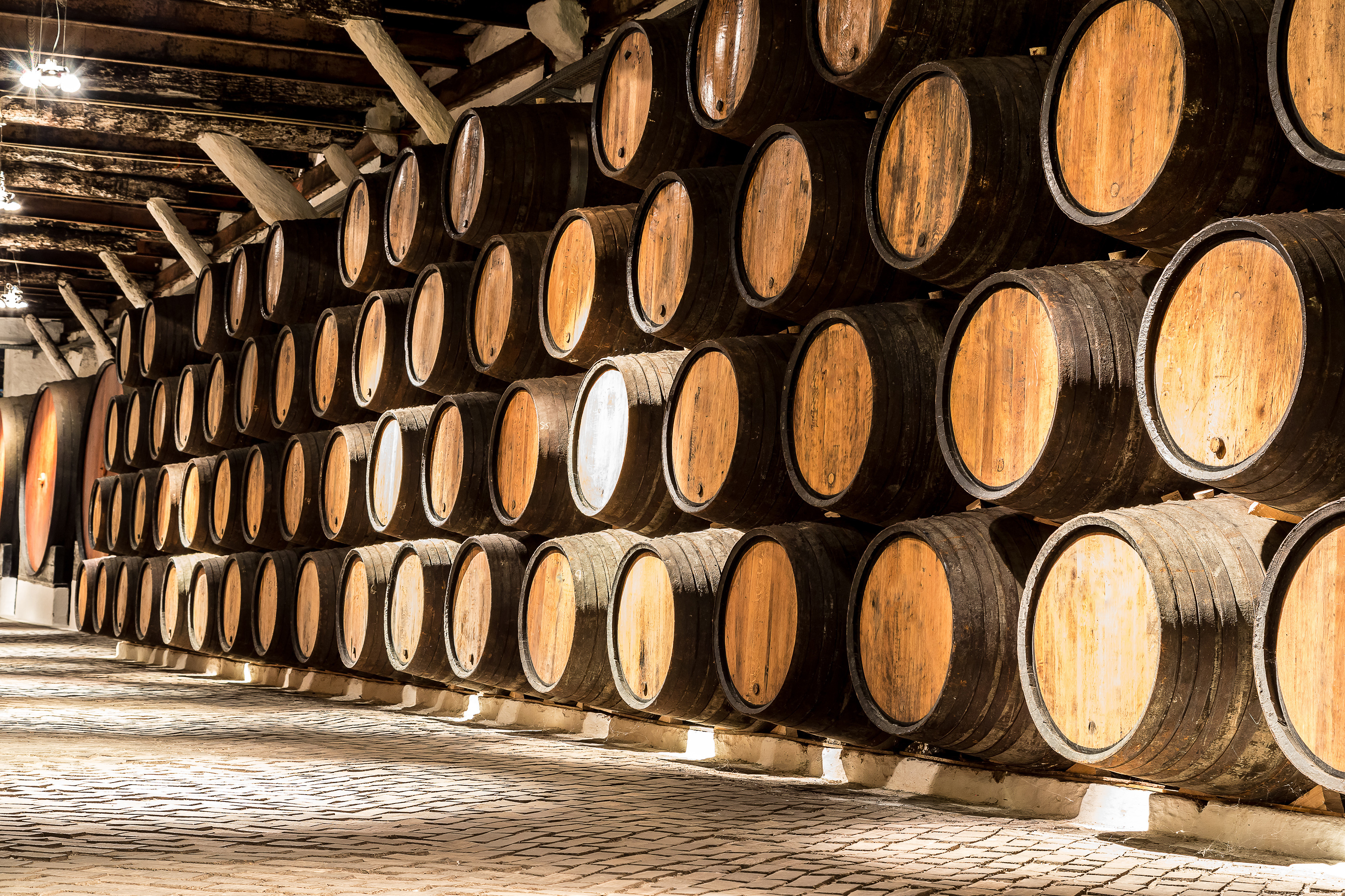 Autentiske egetræstønder med portvin i en historisk vinkælder i Porto, hvor Portugals berømte portvin lagres og modnes i den karakteristiske mørke atmosfære