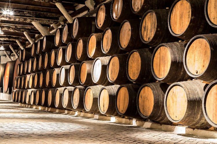 Autentiske egetræstønder med portvin i en historisk vinkælder i Porto, hvor Portugals berømte portvin lagres og modnes i den karakteristiske mørke atmosfære