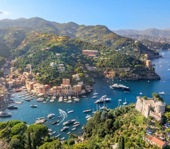 Betagende luftfoto af Portofino i Italien med farverige bygninger, idyllisk havn og frodige grønne bakker ved Middelhavet