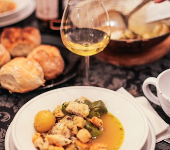 Traditionel portugisisk cataplana med friske rejer og fisk i en duftende sauce med farverige grøntsager, serveret i det karakteristiske kobberkogekar fra Algarve-regionen