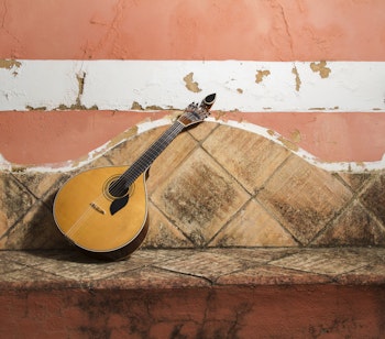 Traditionel portugisisk fado-guitar på stenbænk i Porto, symbol på byens rige musikalske kulturarv og autentiske oplevelser