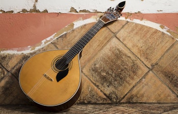Traditionel portugisisk fado-guitar på stenbænk, et ikonisk musikinstrument der symboliserer Portugals rige musikalske kulturarv