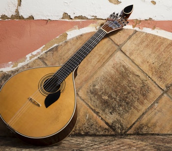 Traditionel portugisisk fado-guitar på stenbænk, et ikonisk musikinstrument der symboliserer Portugals rige musikalske kulturarv