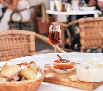 Et glas gylden portugisisk moscatel dessertvin serveret med traditionel lokal ost og brød på en café, en autentisk smagsoplevelse af Portugals rige madkultur