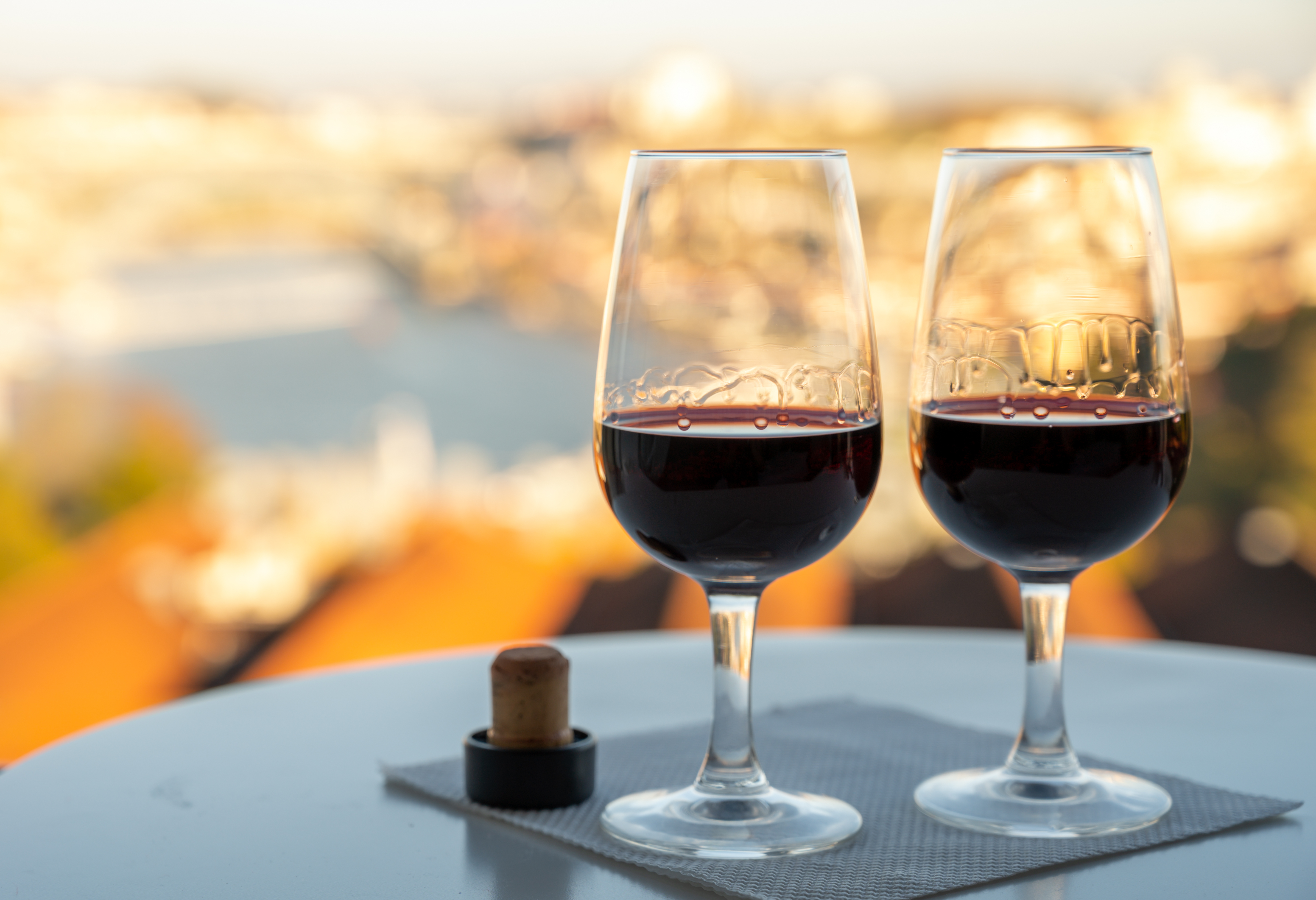 To glas ruby og tawny portvin på en tagterasse med udsigt over Douro-floden og Porto ved solnedgang, Portugal