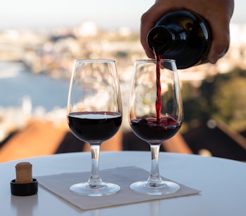 Portvinssmagning med udsigt over Douro-floden, Porto by og vinkældre i Vila Nova de Gaia ved solnedgang i Portugal