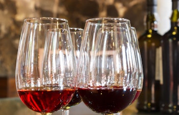 Fire elegante glas med rubinrød portvin arrangeret på mørk baggrund, perfekt til en eksklusiv vinsmagning på din rejse